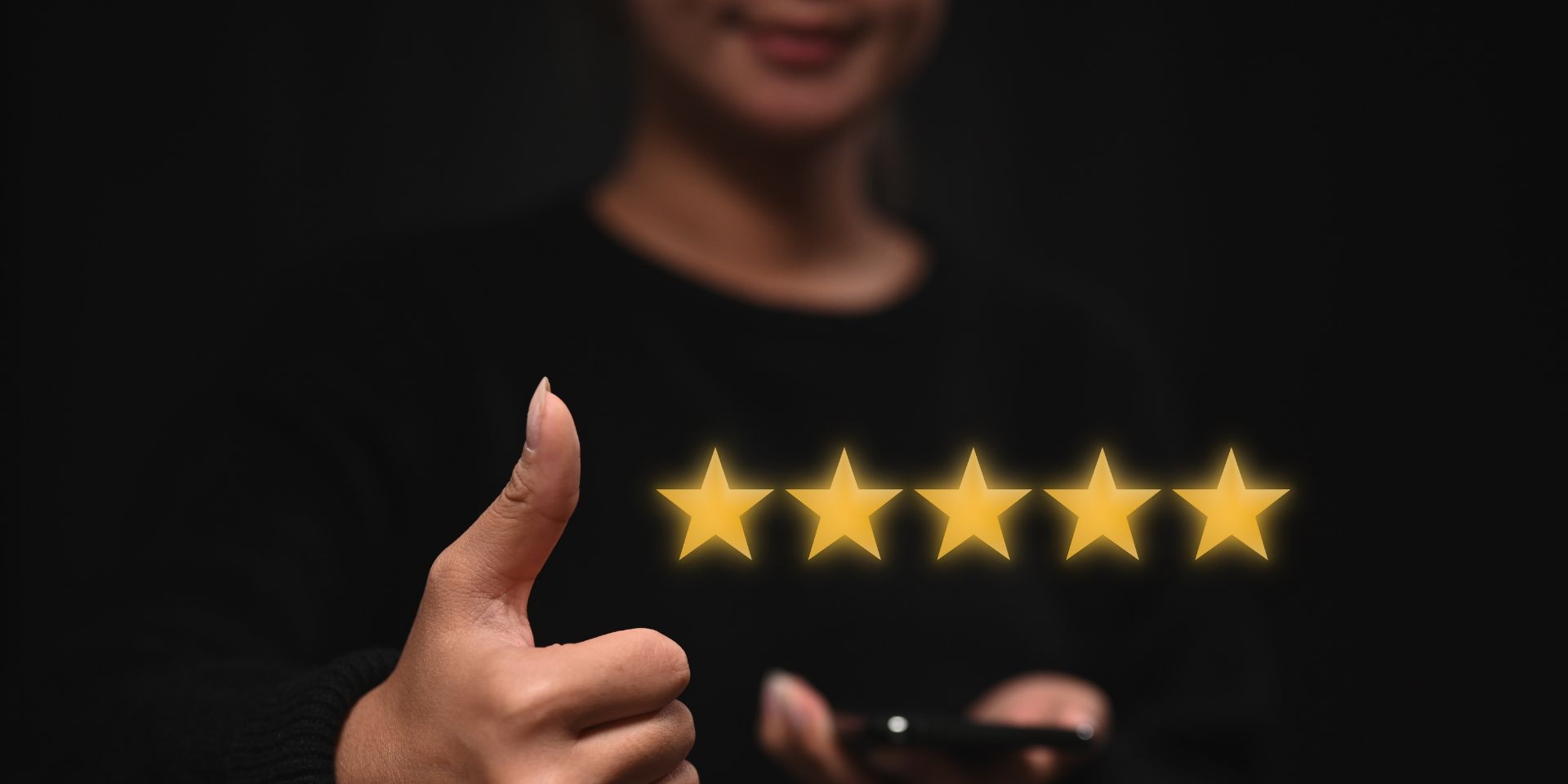 A woman holds her thumb up to five gold stars.