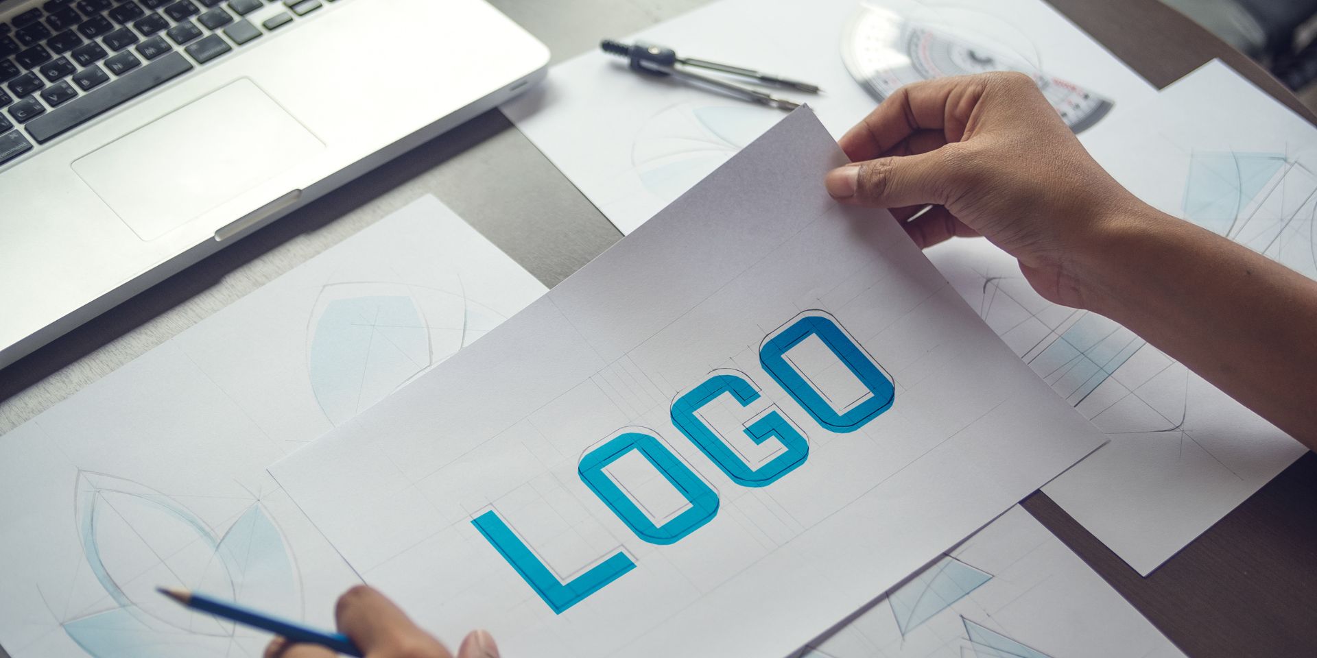 Graphic designer holds a piece of paper with the word 'LOGO' on.