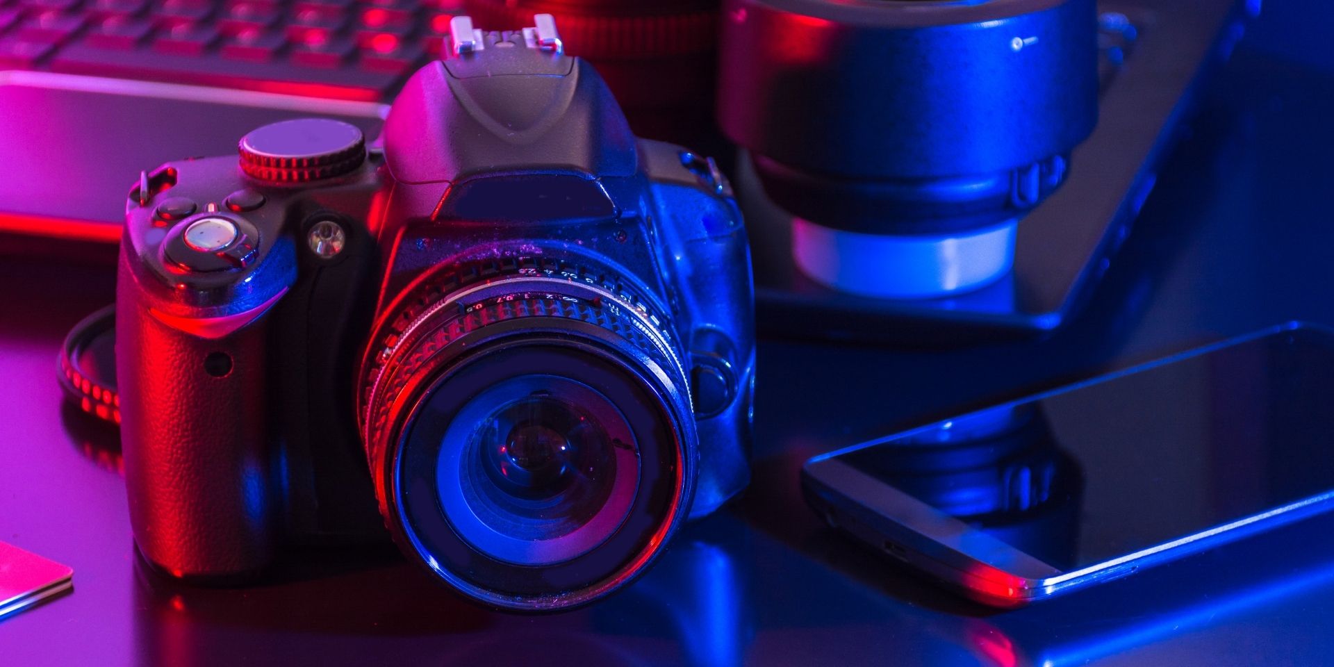 A dramatically lit professional camera and lens rests on a desk.