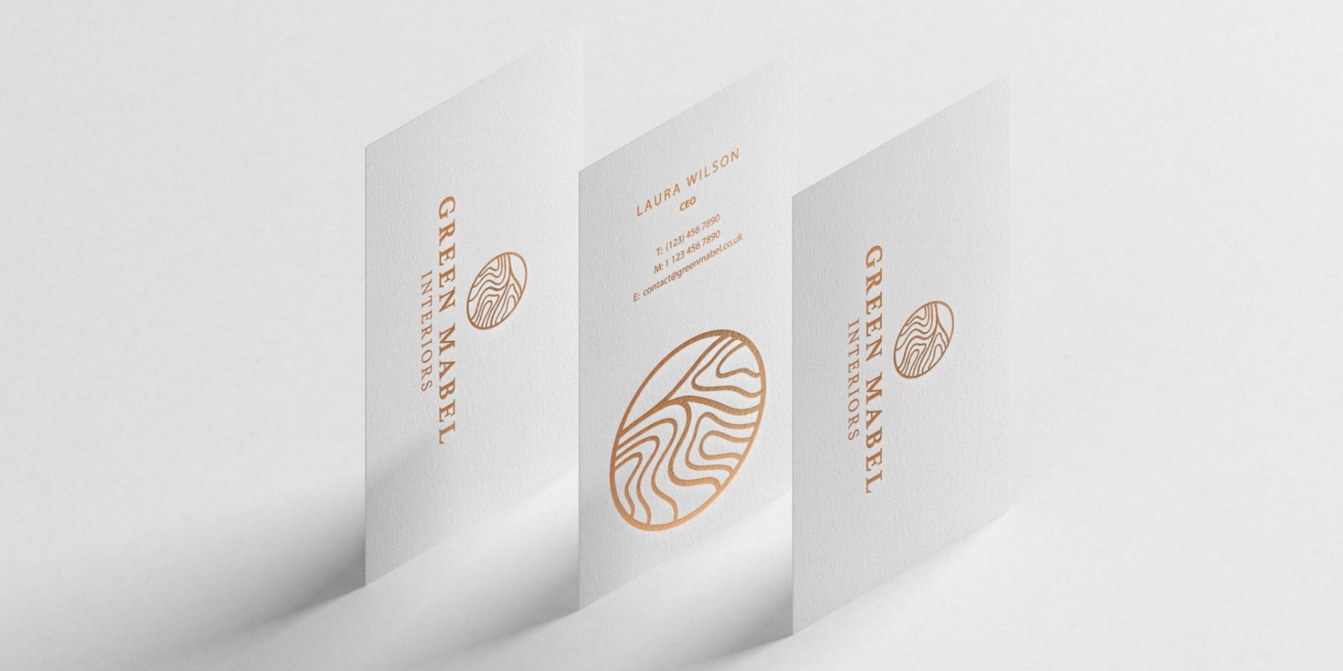 A row of three white and gold business cards are shown.