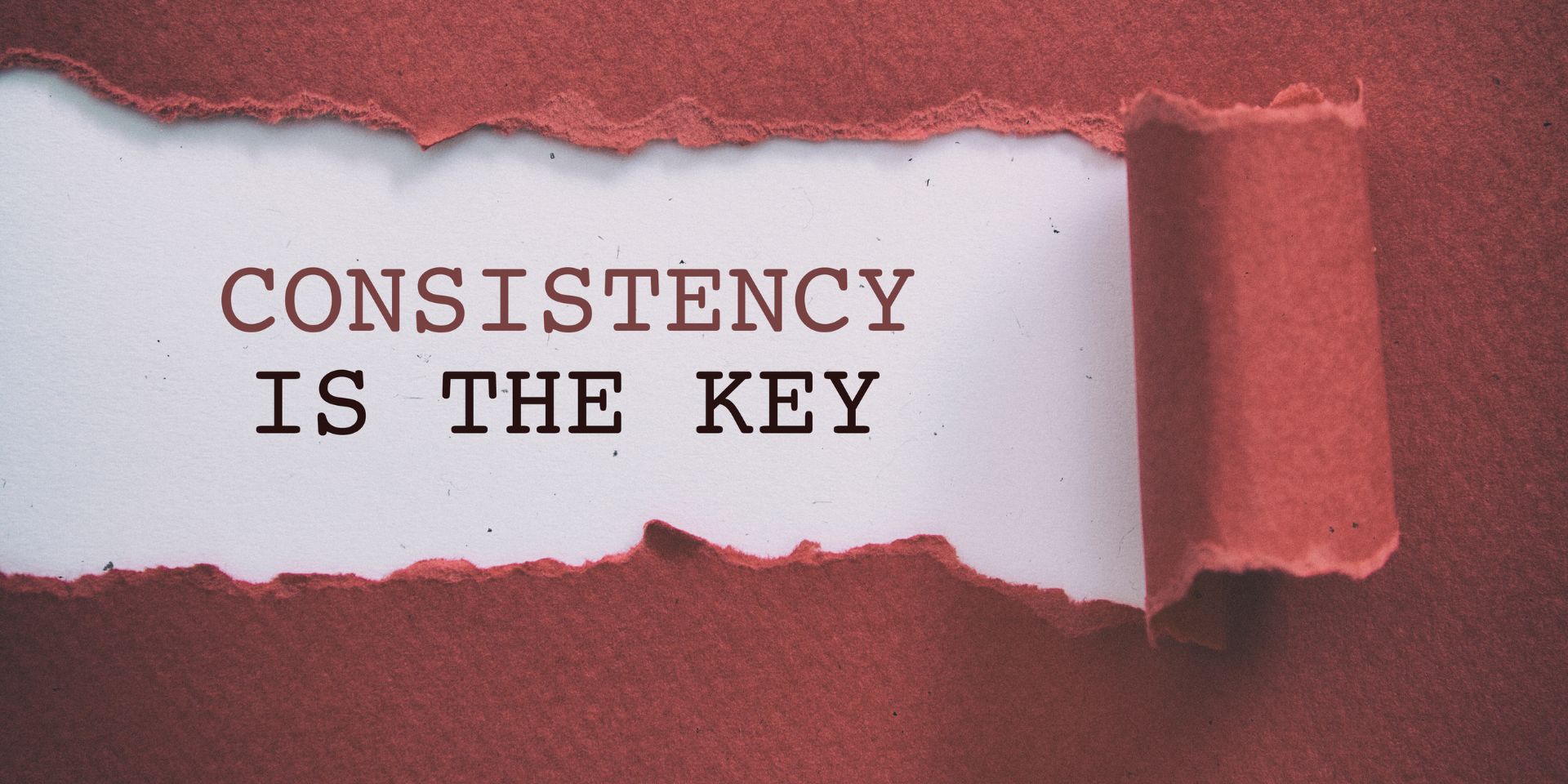 A ripped piece of red paper reveals the words "Consistency is key" underneath.