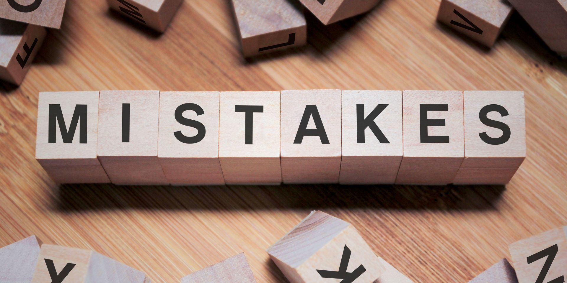 A row of wooden letter blocks spells 'mistakes'.