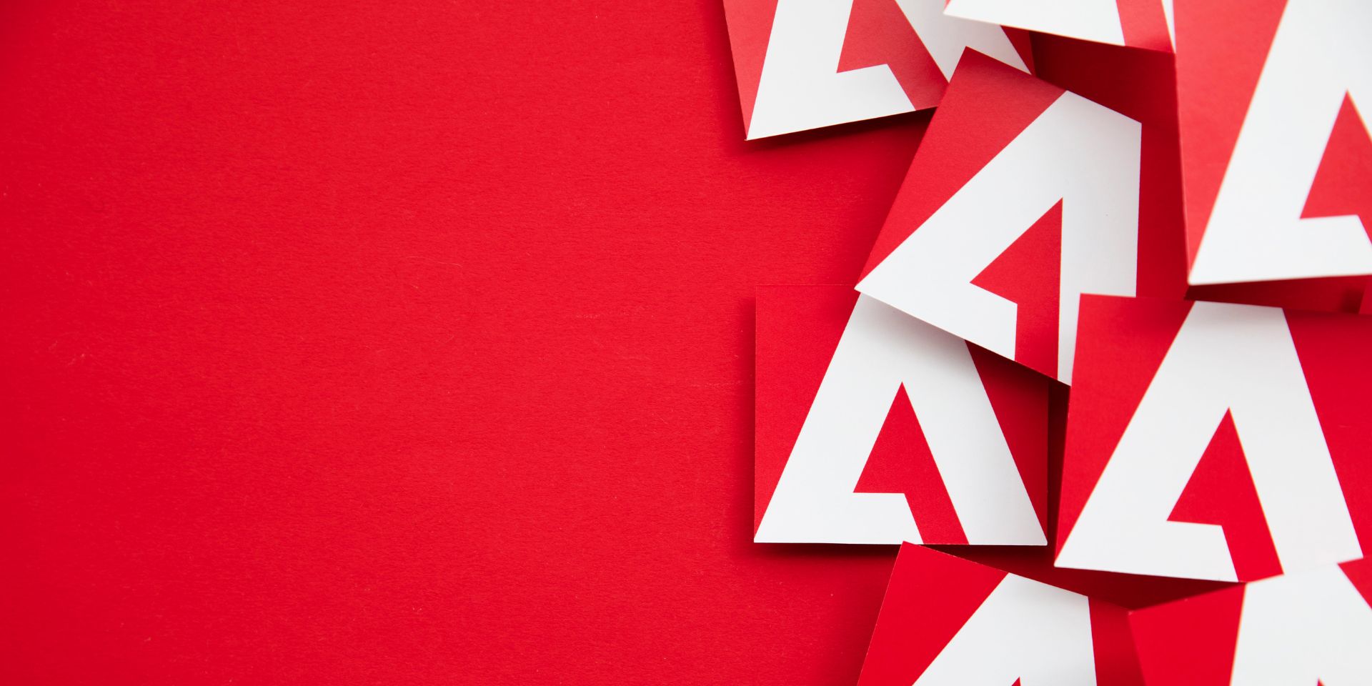 This image shows a collection of Adobe logo tiles against a red background.
