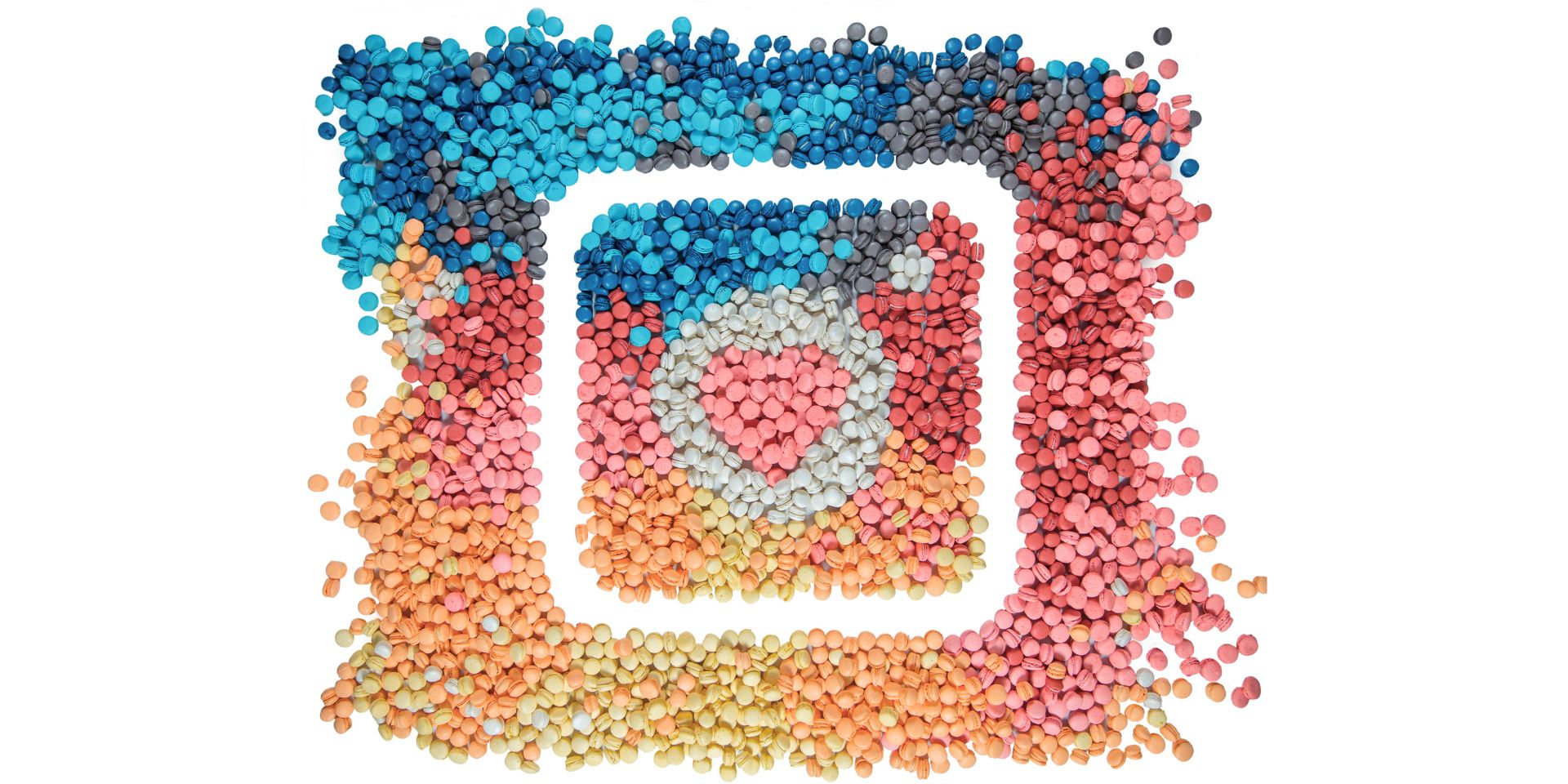 A rainbow of coloured dots are shown on a white background, behind a white Instagram logo.