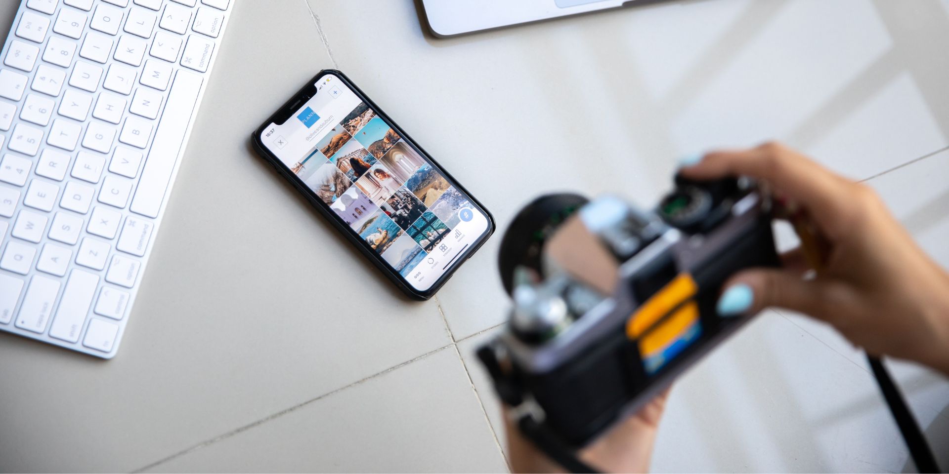 A tiled floor background with a smartphone and computer keyboard is being photographed by a person holding a black DSLR camera.