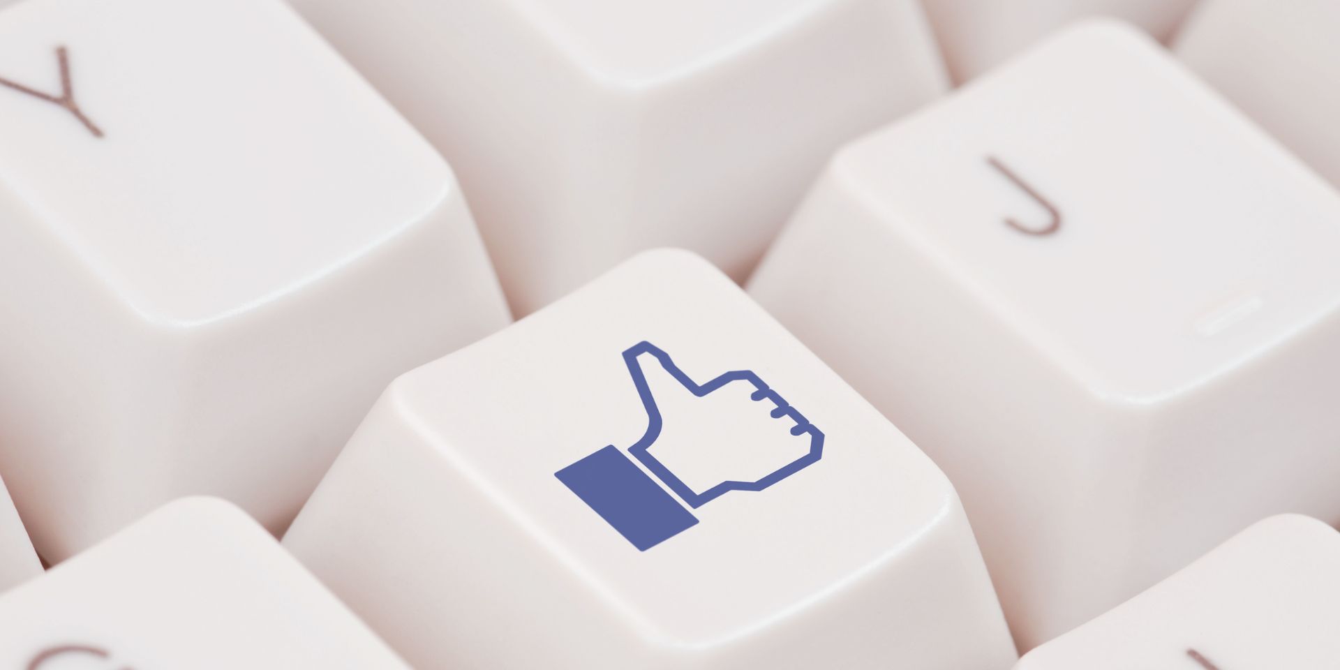 A cream computer keyboard is shown close up, with one of the central key caps showing a Facebook Like icon in dark blue.