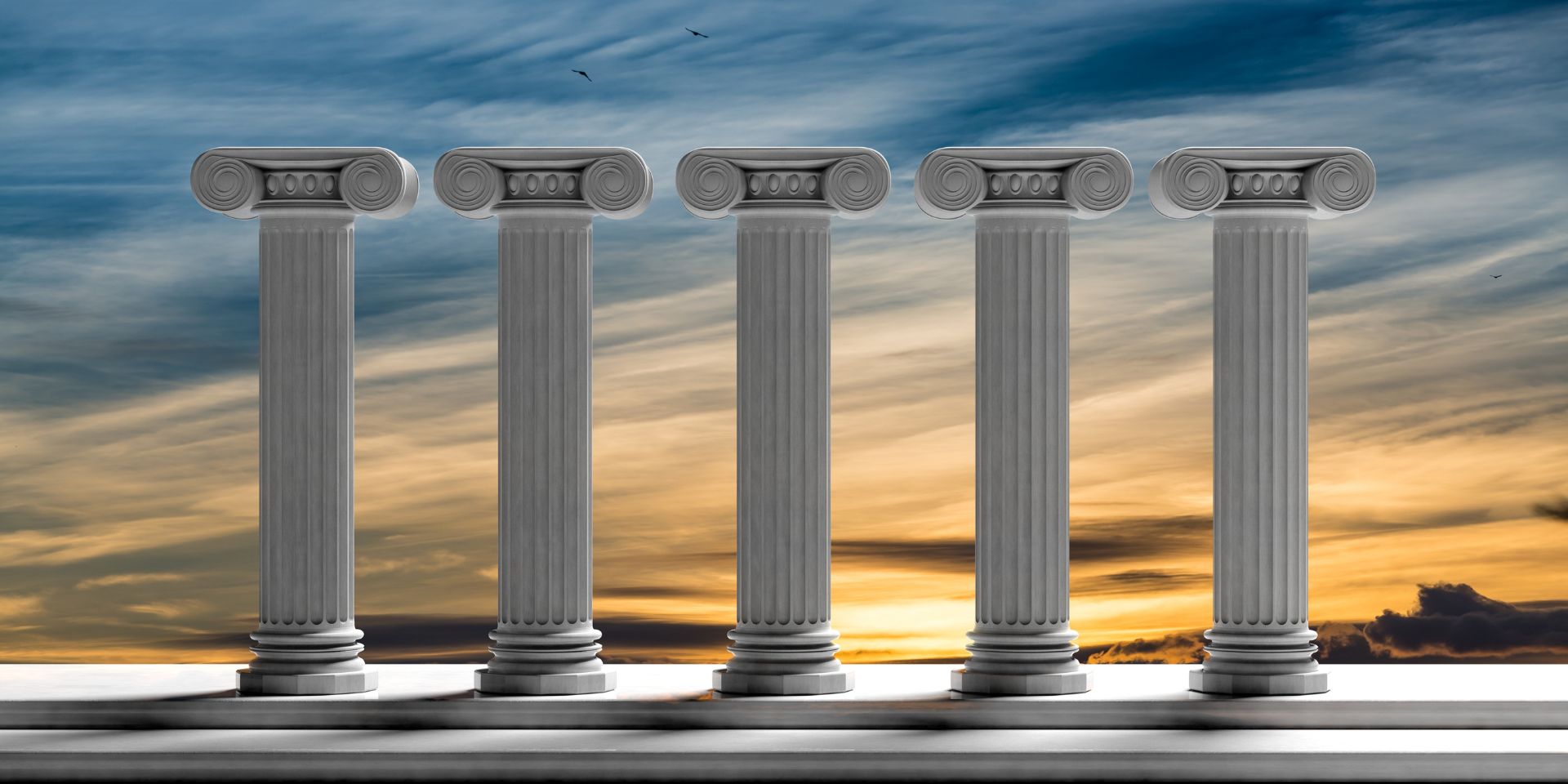 Five Grecian stone pillars standing in front of a sunset background.