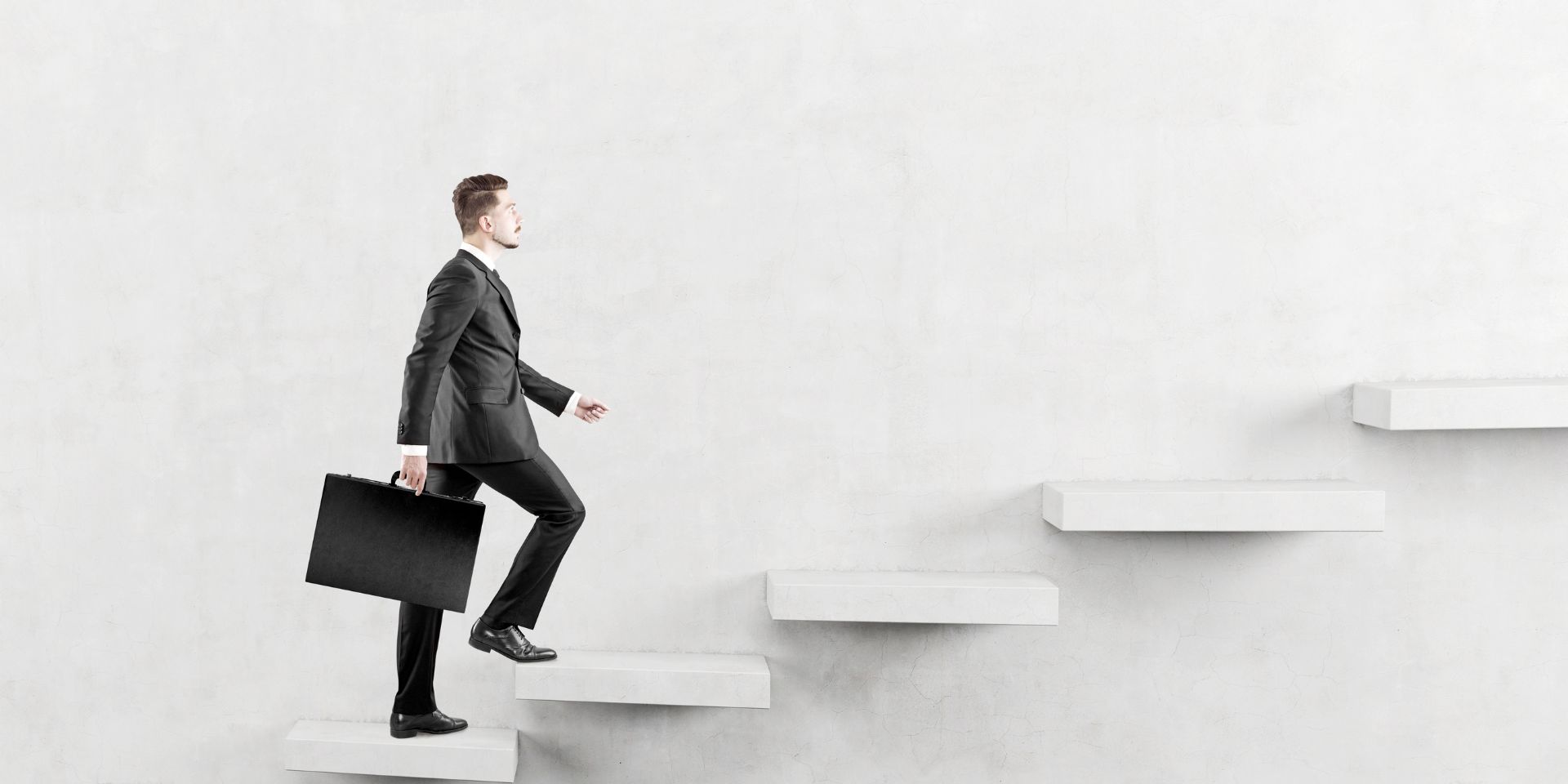 An image of a businessman walking up concrete stairs while holiding a briefcase.