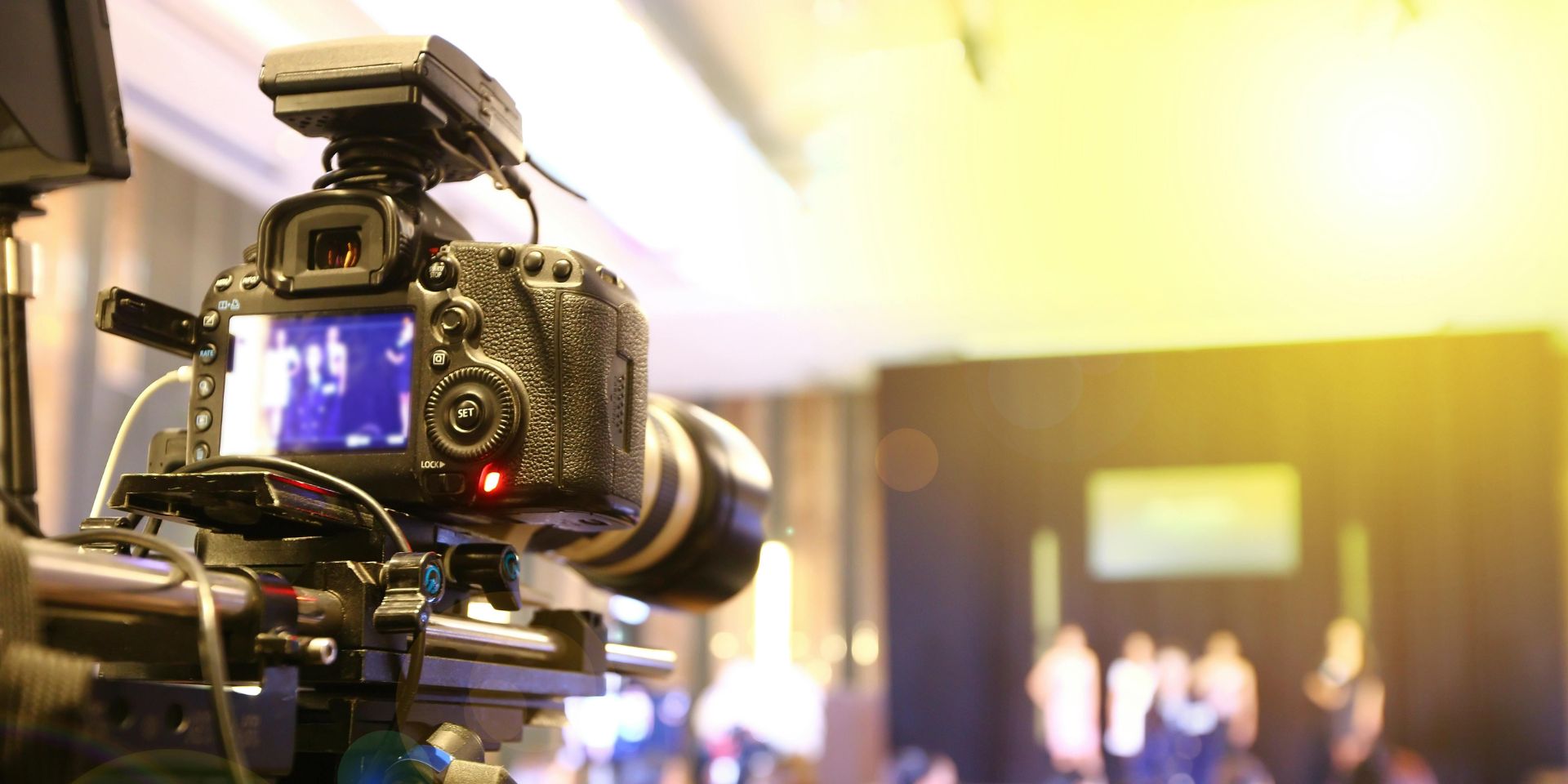A videography film crew recording an event presentation onstage.